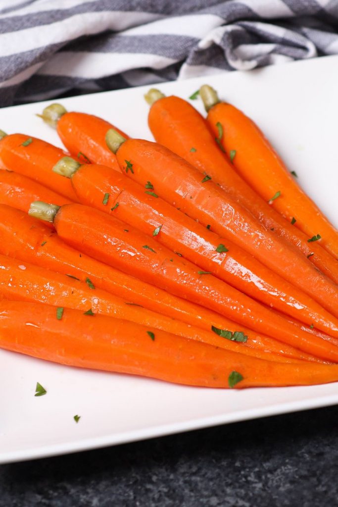 These Sous Vide Honey Glazed Carrots are tender and flavorful carrots simmered in a mixture of honey and butter, then topped with a sprinkling of parsley. The sous vide method transforms the carrots into the perfectly tender pieces. Sweet, savory and full of flavor, this recipe makes an amazing side dish for a holiday dinner or a week day meal. #SousVideCarrots