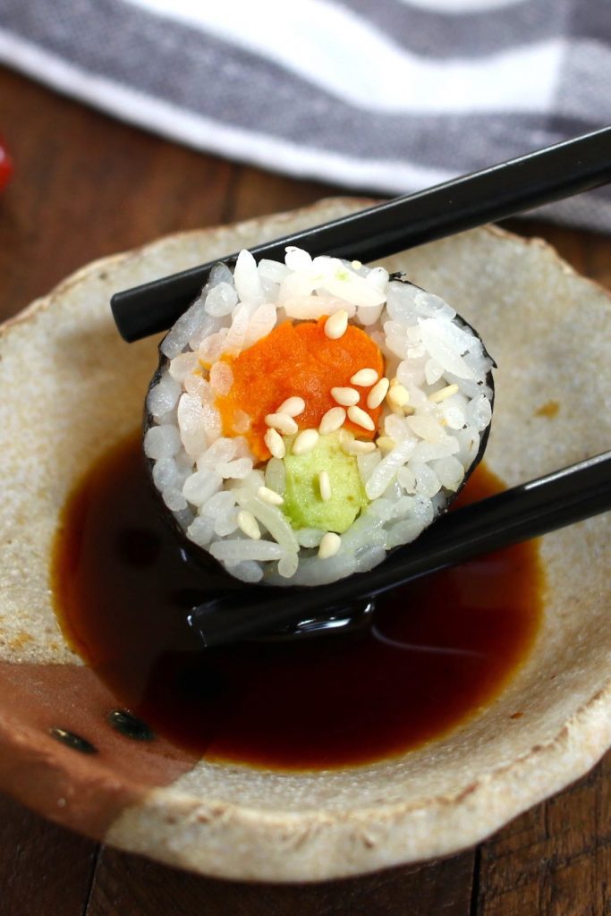 Dipping a piece of sushi roll in soy sauce.