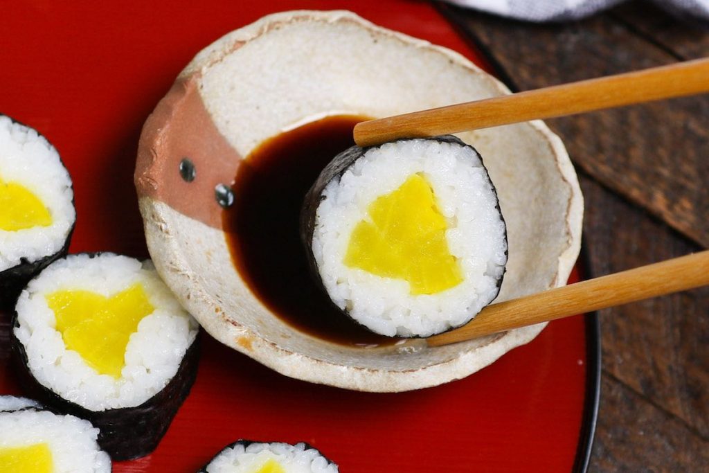 Dipping a piece of Oshinko Roll into soy sauce.