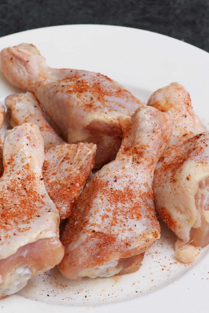 Raw chicken legs rubbed with olive oil and seasoned with garlic powder, paprika, salt and pepper.