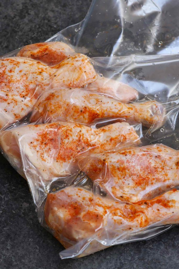 Seasoned chicken drumsticks vacuum-sealed in a zip-top bag.