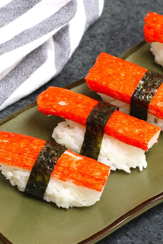 Nigiri sushi using nori strips to secure the imitation crab meat and rice.