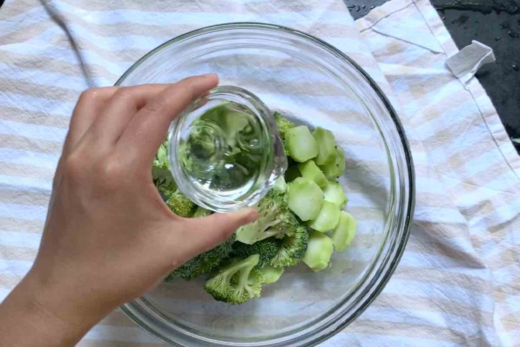 Adding broccoli florets and water into the bowl.