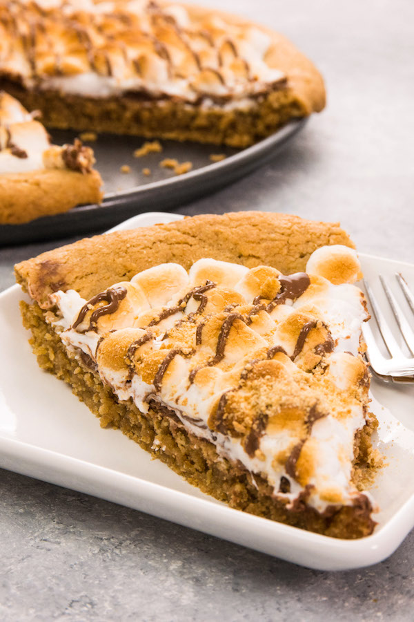 S’mores Pie / S’more Pizza is gooey, chocolatey, rich and crunchy making a perfect crowd-pleaser. It’s such an easy recipe that takes less than 30 minutes. Who needs a campfire? The combination of graham cracker crust, toasted marshmallow and rich chocolate come together, in the form of a delicious pie. So good! Quick and easy recipe. | Tipbuzz.com #smoresPie #smoresPizza