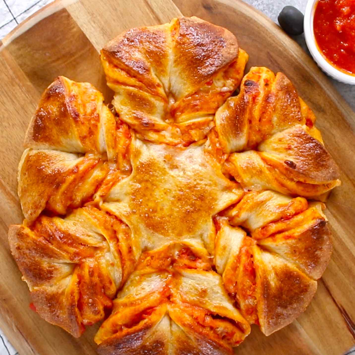 This is one of the easiest pizza recipes that can be prepared in 5 minutes. Put it in the oven and wait for 15-20 minutes and you will get a warm, cheesy and pull apart pizza.  All you need is only 5 ingredients: refrigerated pizza dough, marinara sauce, shredded mozzarella, egg and water. The perfect snack, lunch or quick dinner. 
