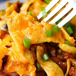 Frito Chili Pie – The best frito pie loaded with Frito corn chips, ground beef, chili beans and tomato sauce. Topped with melted cheddar cheese and more fritos, it is a delicious Mexican-inspired casserole perfect for a quick weeknight dinner!