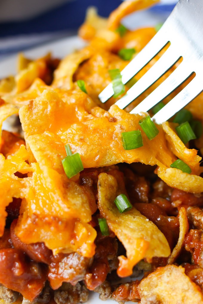 Frito Chili Pie – The best frito pie loaded with Frito corn chips, ground beef, chili beans and tomato sauce. Topped with melted cheddar cheese and more fritos, it is a delicious Mexican-inspired casserole perfect for a quick weeknight dinner!