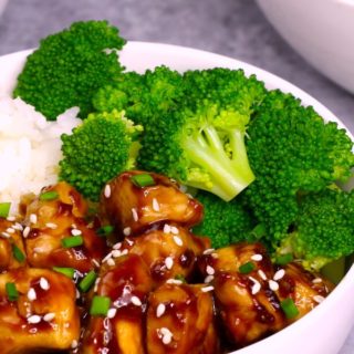 teriyaki chicken served on top of rice with steamed broccoli in a white bowl