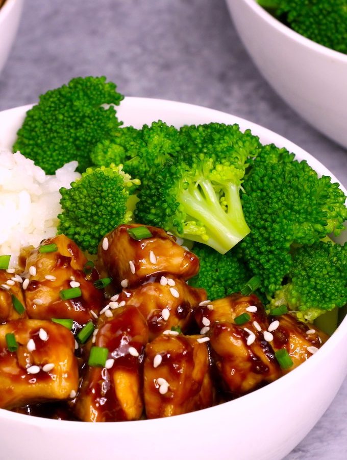 teriyaki chicken served on top of rice with steamed broccoli in a white bowl