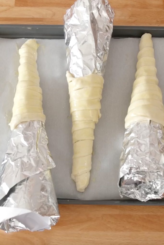Wrap pizza dough strips around the aluminum foil to form cones