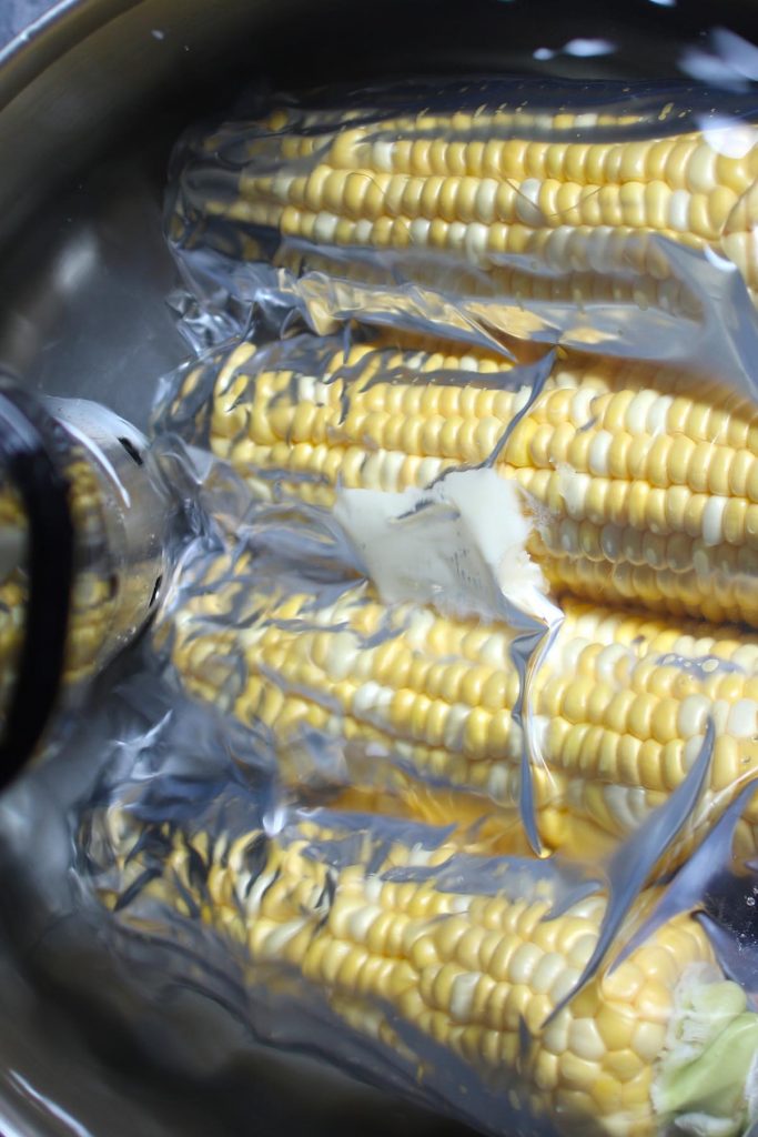 4 ears of corn being cooked in a sous vide machine.