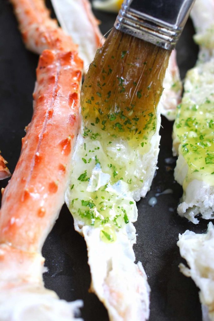 Brushing crab legs with the mixture of melted butter and chopped parsley.