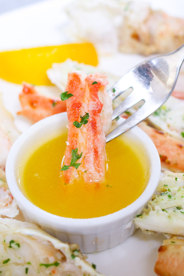 Closeup of king crab meat dipping into melted butter.