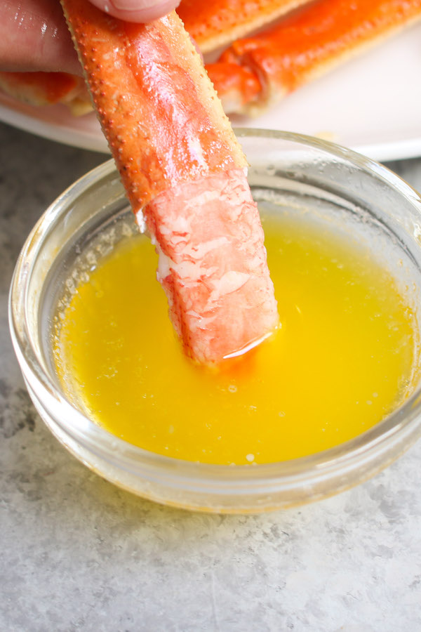 Closeup of snow crab meat dipping into melted butter.