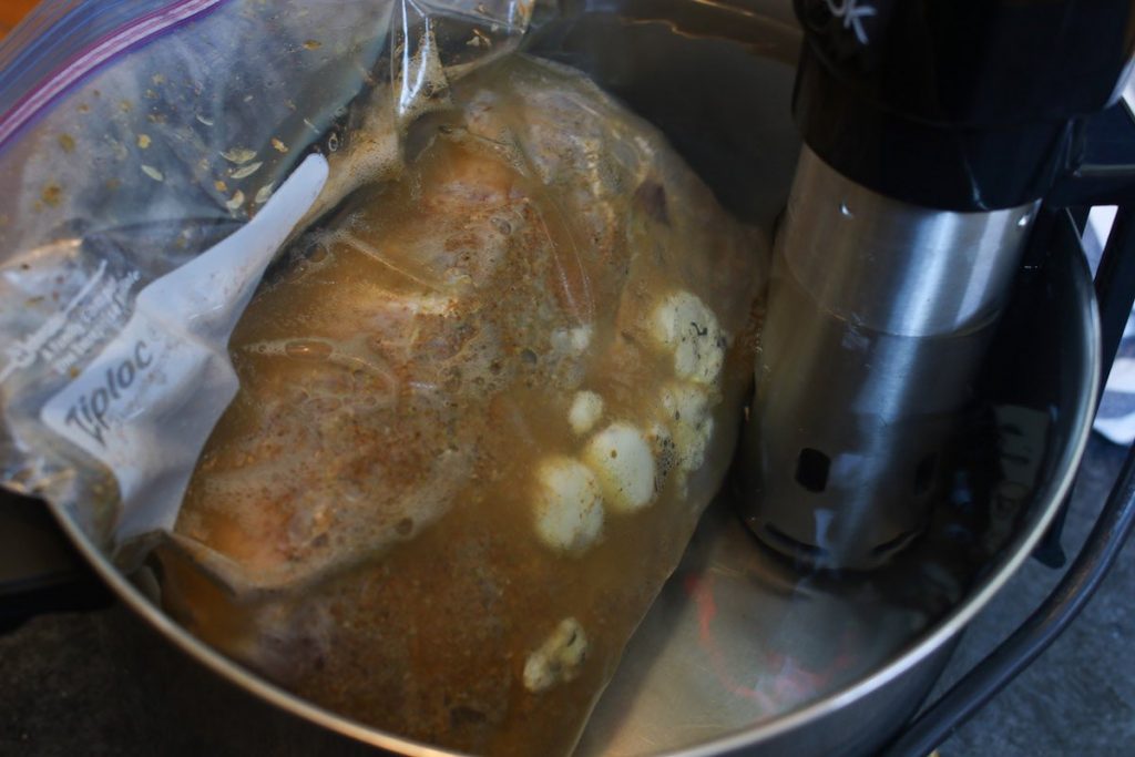 Vacuum-sealed pork shoulder being cooked in the sous vide warm water bath.