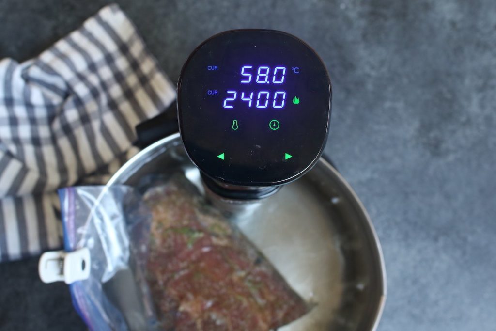 Vacuum-sealed chuck roast being cooked in a sous vide warm water bath.