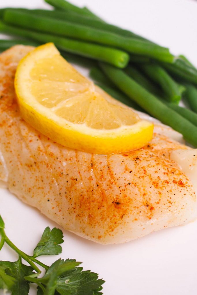 Sous vide cod served with green beans on a white plate.