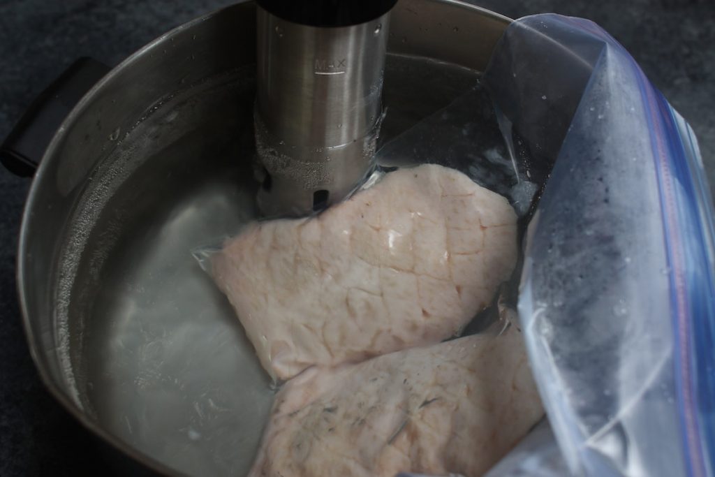 Sous Vide cooking vacuum-sealed duck breasts in a warm water bath.