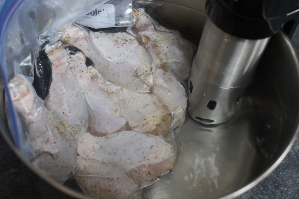 Vacuum-sealed chicken drumsticks in the warm water bath.
