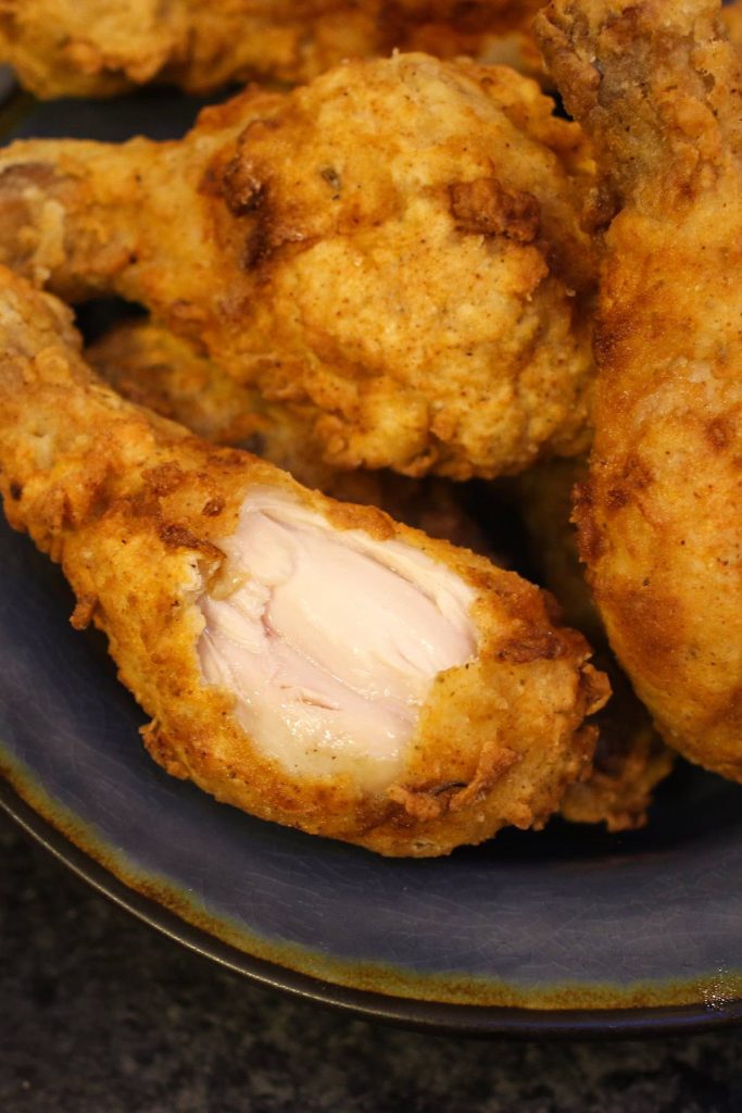Close-up of a cross-section of fried chicken with crispy crust and tender and juicy texture.
