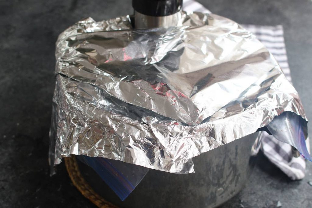 Covering the pot with a few pieces of aluminum foil.