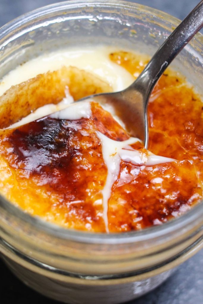 Closeup showing cracking the creme brûlée with a spoon.