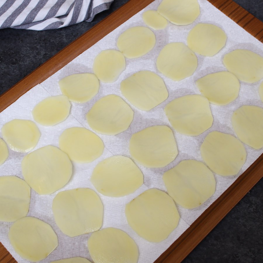 Placing potato slices on the paper towel in one single layer.