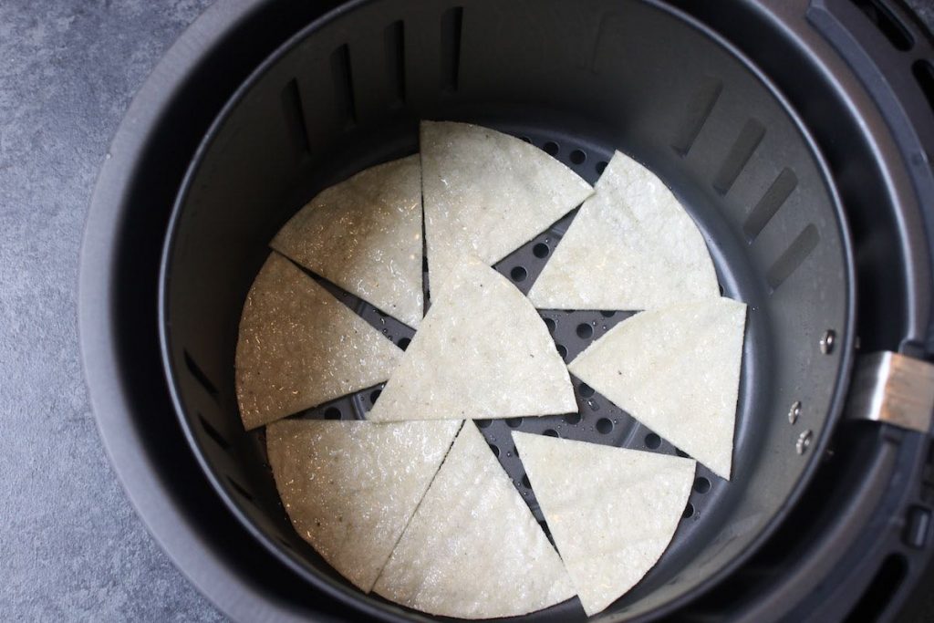 Spreading the tortilla pieces in the air-fryer basket in a single layer.
