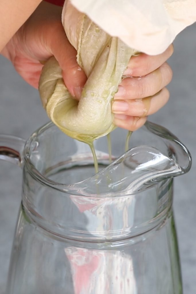 Using hands to squeeze the juice through the nut milk bag.