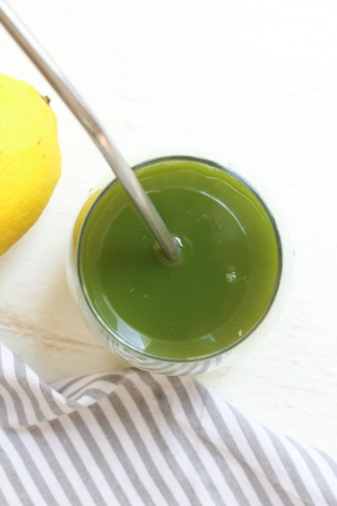 A glass of celery juice on a white board.