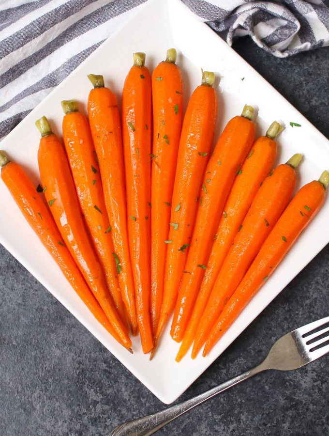 These Sous Vide Honey Glazed Carrots are tender and flavorful carrots simmered in a mixture of honey and butter, then topped with a sprinkling of parsley. The sous vide method transforms the carrots into the perfectly tender pieces. Sweet, savory and full of flavor, this recipe makes an amazing side dish for a holiday dinner or a week day meal. #SousVideCarrots