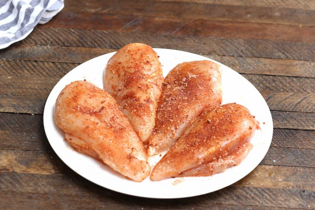 Season raw chicken breasts with paprika, garlic powder, salt and pepper.