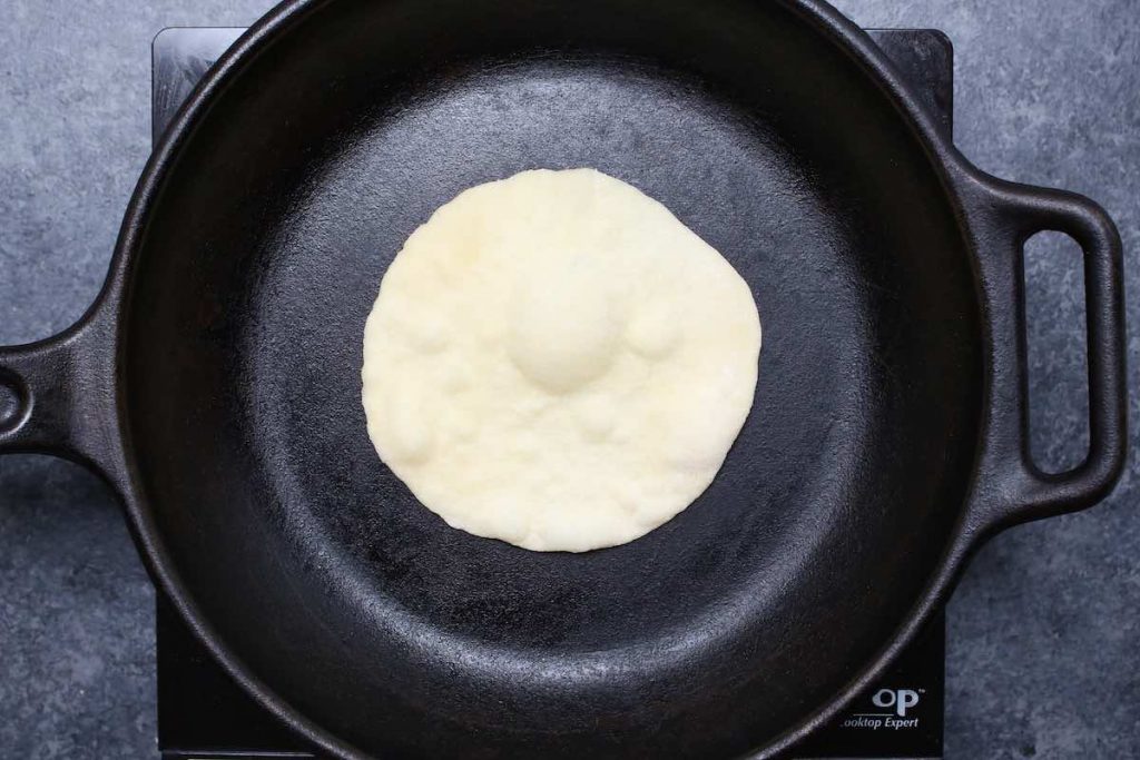 Cooking the tortilla in a hot cast-iron skillet.