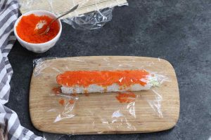 Placing a piece of plastic wrap on top of the tobiko.