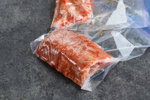 Seasoned ribs vacuum sealed in zip-top bags.