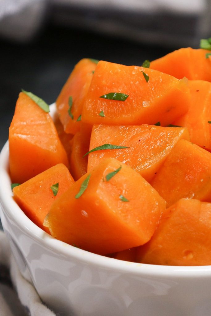 Sous vide sweet potatoes served in a white bowl, and topped with seasonings and chopped parsley.