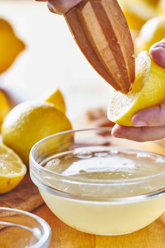 Juicing a fresh lemon into a clear bowl.