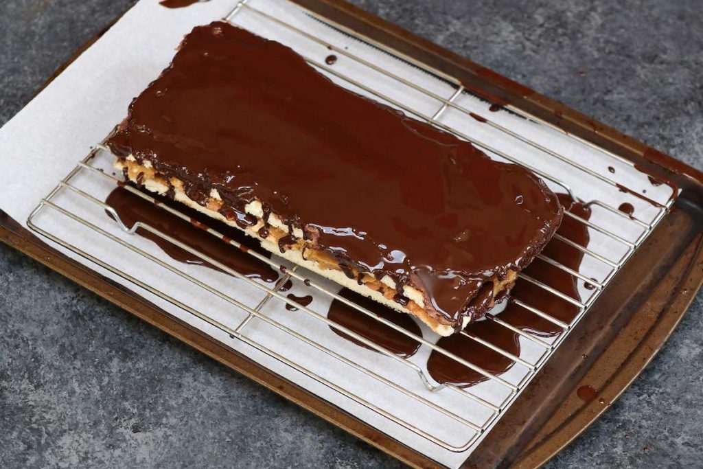 Pouring chocolate glaze over the chilled opera cake.