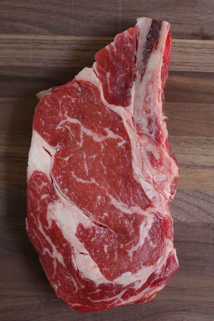 Raw ribeye steak on a cutting board.