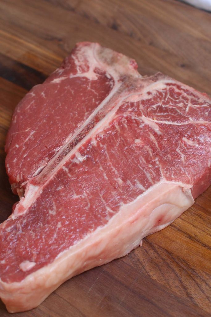 A raw t-bone steak on the cutting board.