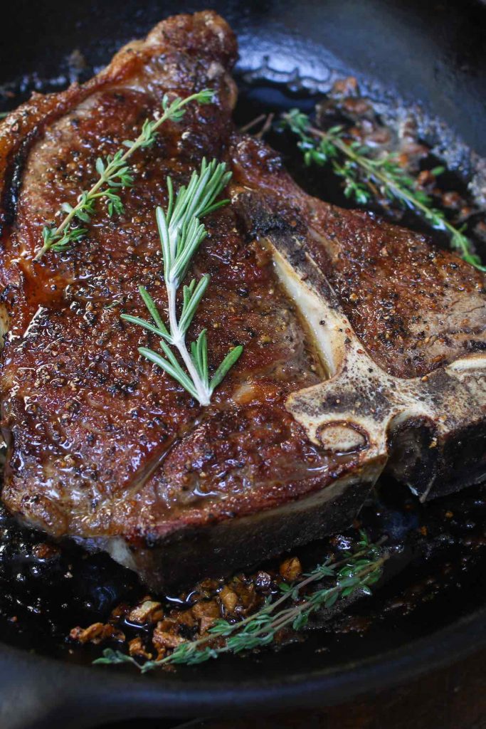 Searing t-bone steak in a hot skillet.