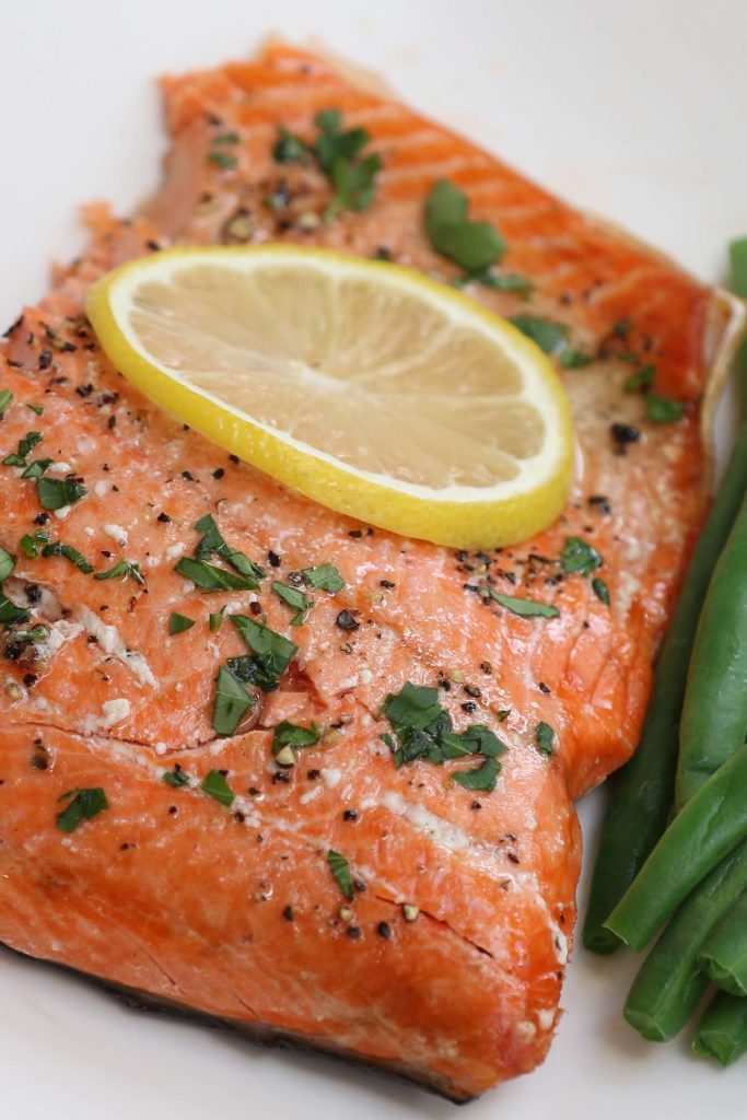 Sous vide salmon served with green beans on a white plate.