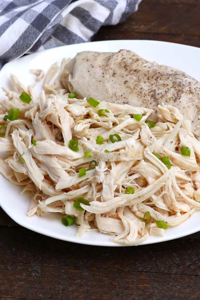 Shredded sous vide chicken breasts on a white plate to be served.