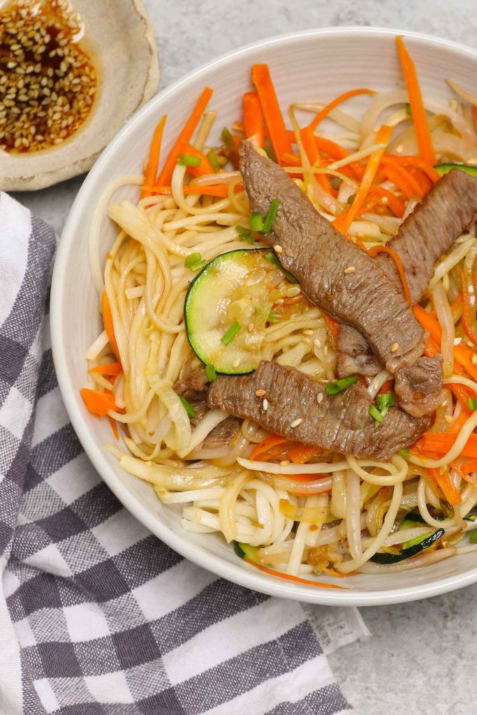 Mongolian BBQ beef, vegetables, and noodles served in a white bowl.