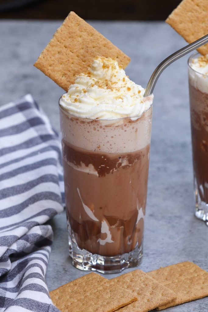 Bring your favorite coffee shop drink home! This copycat Starbucks S’mores Frappuccino is creamy, chocolatey, and full of marshmallow, coffee, and graham crackers flavor. Made with a few simple ingredients, it gives you all the summer refreshing taste of the Starbucks Campfire Smores Frap at the fraction of the price! #SmoresFrap #StarbucksSmoresFrap #SmoresFrappuccino