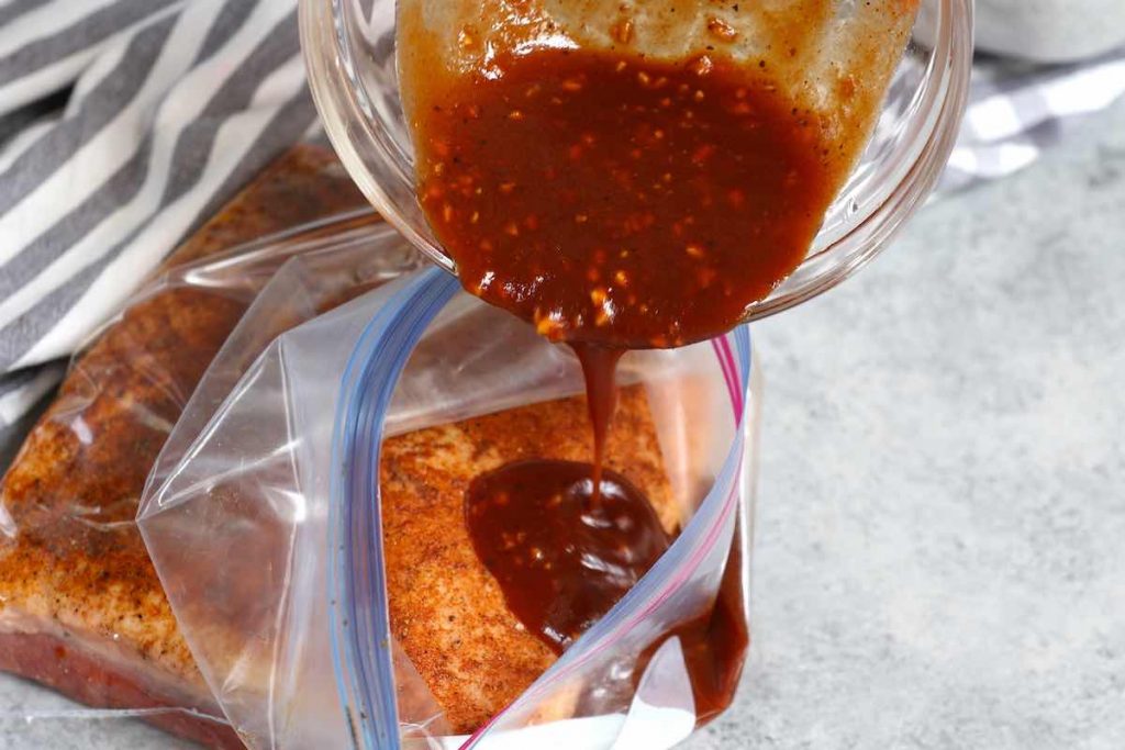 Pouring the BBQ sauce over the brisket in a ziptop bag.