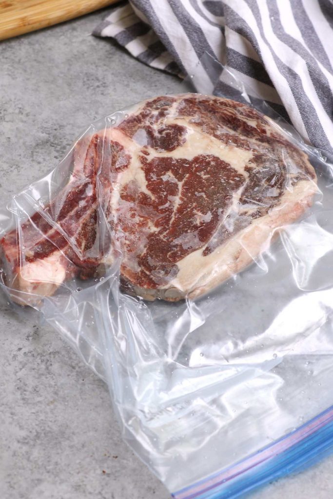 Frozen rib-eye steak vacuum-sealed in a zip-top bag.