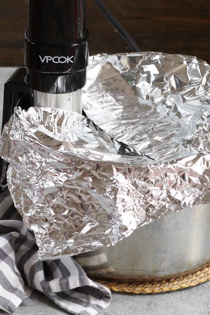 Brisket cooked in a sous vide water bath and covered with aluminum foil.