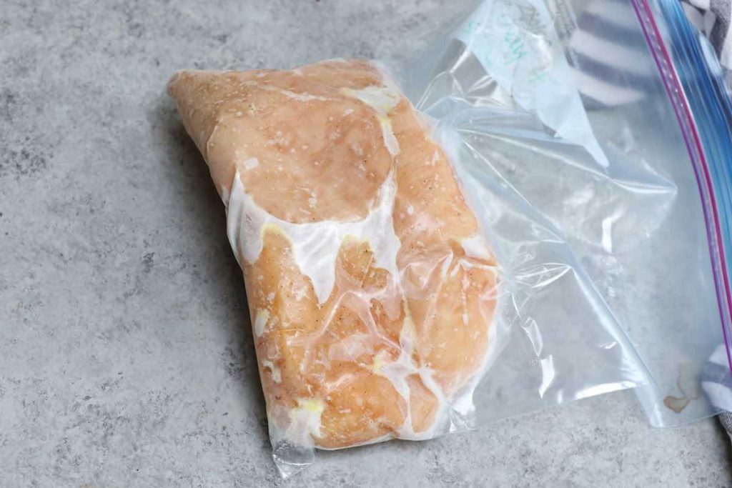 Frozen chicken breasts vacuum-sealed in a zip-top bag.