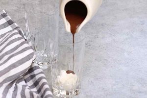 Drizzling chocolate sauce on top of the whipped cream.